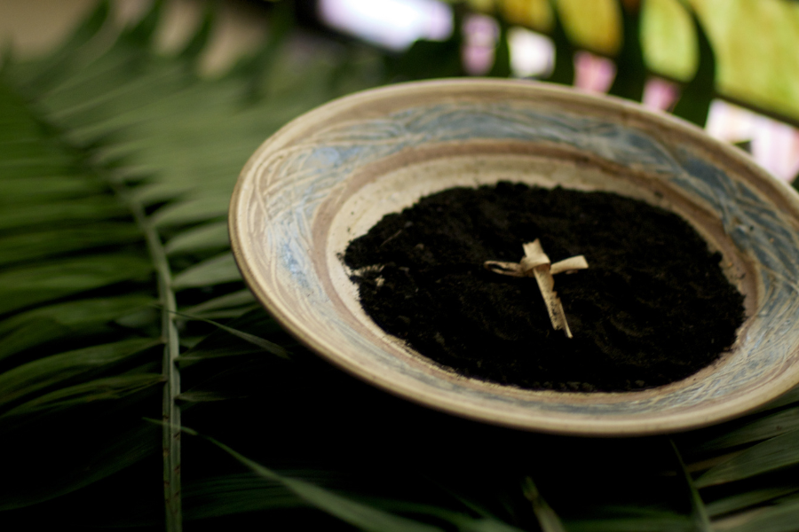 A palm cross lying on top of a bowl of ashes