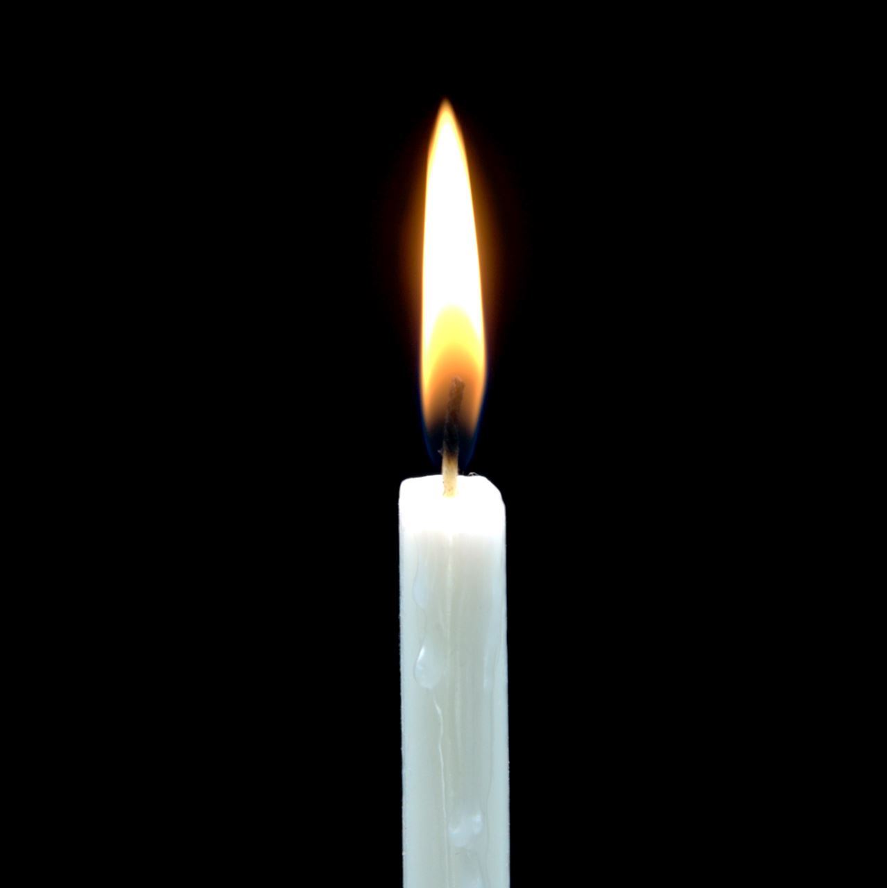 Thin, white lit candle against black background