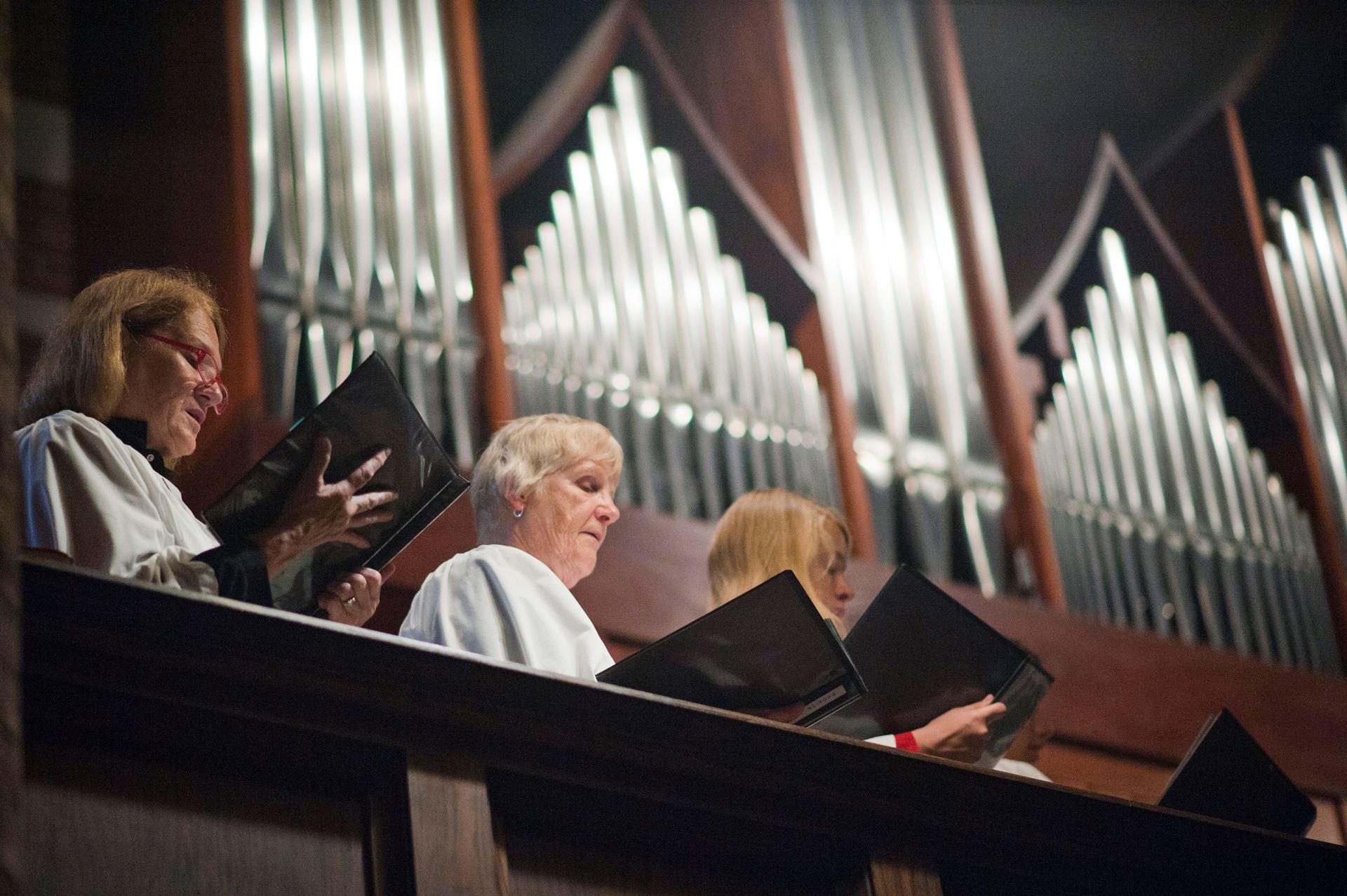 Members of Parish of the Epiphany's choir singing in choir loft in front of pipe organ
