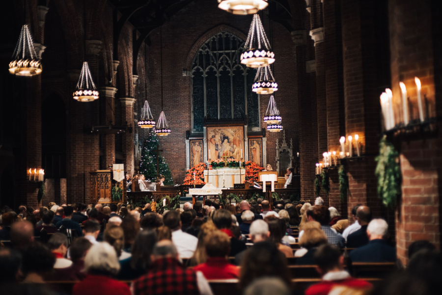 Parish of the Epiphany's nave full of people, lit candles, and greenery during Christmas Eve worship