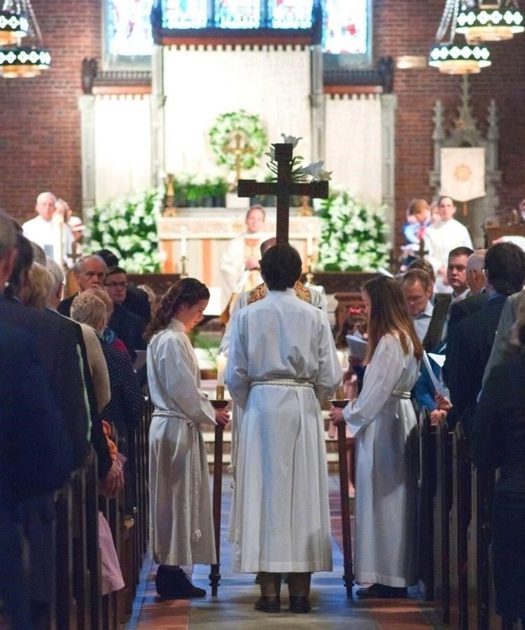 Gospel Procession at Parish of the Epiphany. Clergy and acolytes in white stand in the center aisle of the sanctuary.