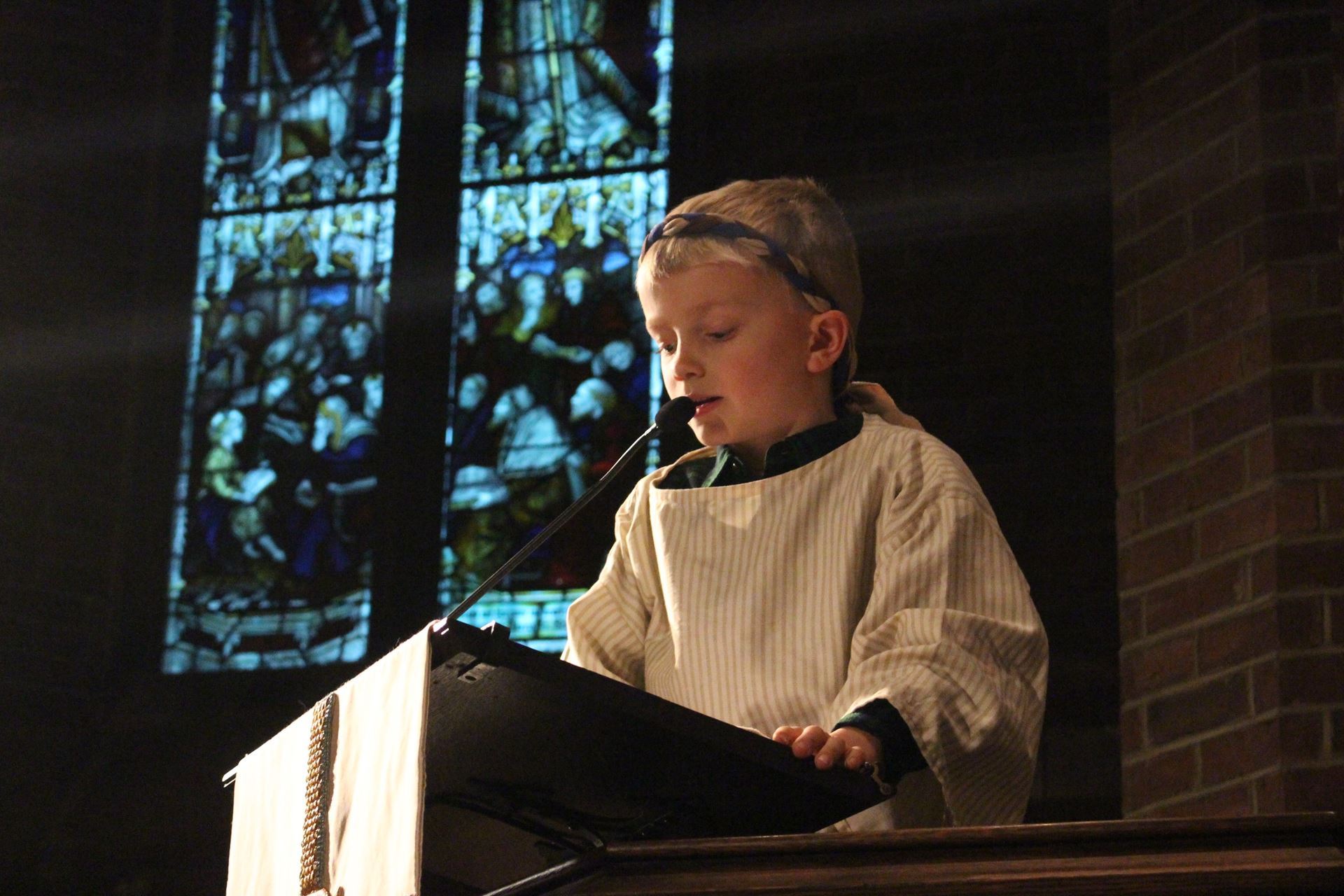 Costumed child reading at lectern during Parish of the Epiphany's Christmas pageant