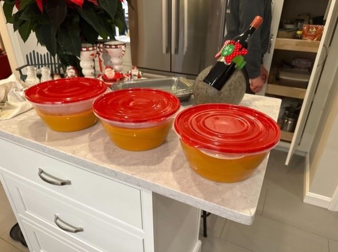 Three Tupperware bowls containing carrot soup